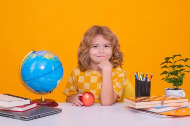 Kid boy from elementary school with book on yellow isolated background. Little student, smart nerd pupil ready to study. Concept of education and learning