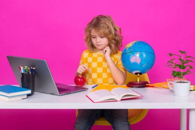 Dizüstü bilgisayar kullanan okul çocuğu. İlkokuldan elinde kitapla bir çocuk. Küçük öğrenci, zeki inek öğrenci çalışmaya hazır. Okula ilk gelişim. Eğitim ve öğrenim kavramı