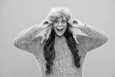 Teenager girl with winter hat over isolated yellow background. Winter christmas holidays, new year mood. Kids warm clothes. Excited face, cheerful emotions of teenager girl