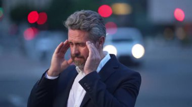 Yorgun iş adamı streslidir. Yorgun iş adamı fazla mesai yapıyor ve başı ağrıyor. Başı ağrıyan takım elbiseli bir iş adamı. Üzgün adamın ağrıdan dolayı migreni tuttu. Baş ağrısı migreni..