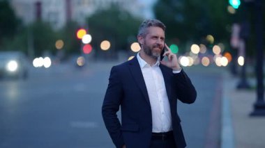 Telefon görüşmesi. İş görüşmesi. Açık havada başarılı bir iş adamı. İş adamı telefonu kullanır. Takım elbiseli olgun iş adamı. Şirket işi. Takım elbiseli zengin İspanyol işadamı.