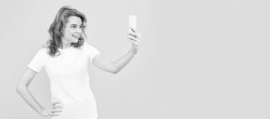 Happy girl smile to mobile camera phone yellow background, video selfie. Woman isolated face portrait, banner with mock up copy space