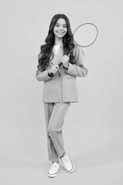 Teen girl badminton player in suit with badminton racket isolated on yellow background