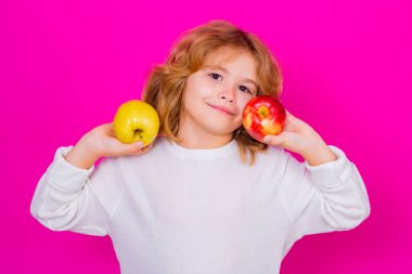 Kid with apple in studio. Studio portrait of cute child hold apple isolated on pink background
