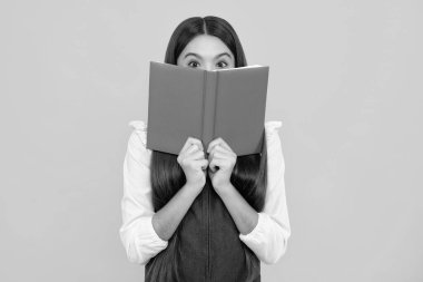 Kopya kitabı olan liseli kız izole edilmiş arka planda poz veriyor. Edebiyat dersi, ilkokul. Entelektüel çocuk okuyucu