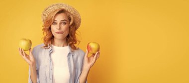 Summer female model with apple. cheerful young woman in summer straw hat with apple licking lips, yummy. Woman isolated face portrait, banner with mock up copy space