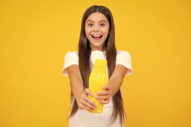 Plastik şişeden su içen genç bir kız çocuğu izole bir arka planda, kopyalama alanı. Çocuk bakım vücut sıvısı. Aktif eğlence ve su dengesi. Heyecanlı bir genç, şaşkın ve neşeli duygular içinde