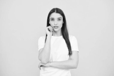 Zevkli bir kadın model tatmin edici görünüyor. Sarı arka planda izole edilmiş güzel bir kadının stüdyo portresi