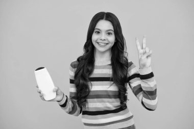 Teenage girl with shampoos conditioners or shower gel. Kids hair care cosmetic product, shampoo bottle. Happy teenager, positive and smiling emotions of teen girl