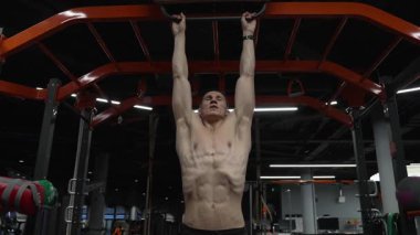 Güçlü gövde kası olan kaslı bir sporcu. Spor barfiks egzersizi. Spor eğitimi. Sporcu adam barfiks egzersizi yapar. Kas kasları ve trisepsler. Güçlü bir atlet. Spor salonunda bir adam var..