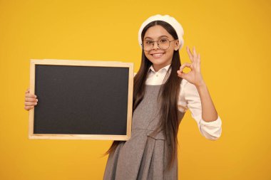 Okul satış kurulu. Neşeli genç kız, sarı arka planda fotokopi alanı olan karatahta tutuyor. Mutlu yüz, pozitif ve gülümseyen genç kız duyguları