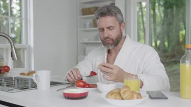 İnsan yemek yer. Sabah kahvaltısı. Sabahları sağlıklı bir kahvaltı. Olgun bir adam mutfakta kahvaltı yapıyor, sağlıklı bir yaşam tarzı. İspanyol adam kahvaltı yapıyor. Sabah yemeği nefis..