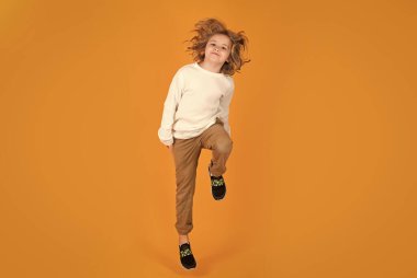Funny boy jumping in air. Full body of little child jump wear casual t-shirt and jeans isolated on yellow background