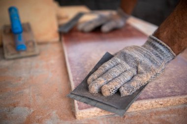 Manos de hombre lijando madera con guantes 