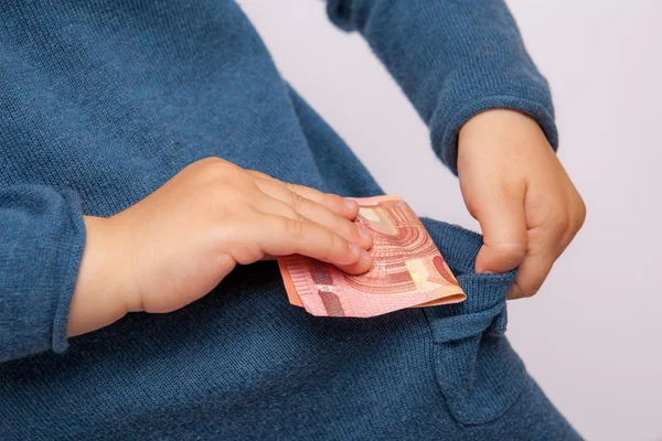 La mano de un niño pequeño pone un billete de diez euros en su bolsillo — Foto de Stock