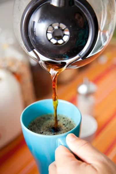 woman pouring coffee pot  into coffe mug