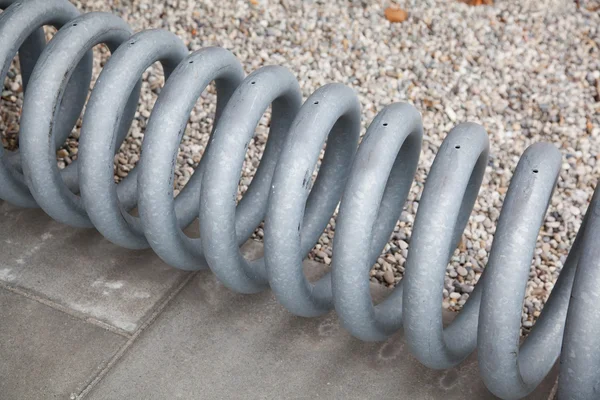 bike stand spiral on concrete floor with gravel.