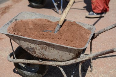 Old rusty iron cart with shovel full of sand