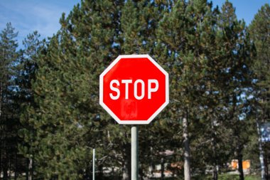 Red-white stop sign at park. In the background is forest. clipart