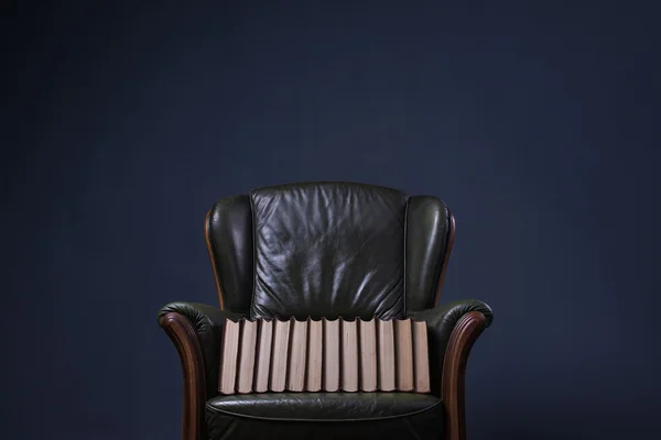 Green leather armchair with books in front of the wall — Stock Photo, Image