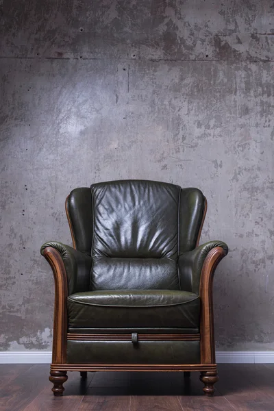 Зеленое кожаное кресло перед стеной — стоковое фото