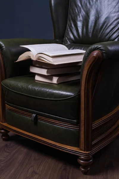 Green leather armchair with books in front of the wall — Stock Photo, Image