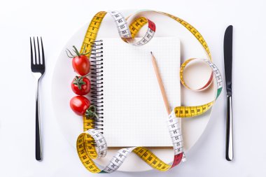 Tabak, çatal, bıçak, ölçüm bant, kalem, domates ve defter