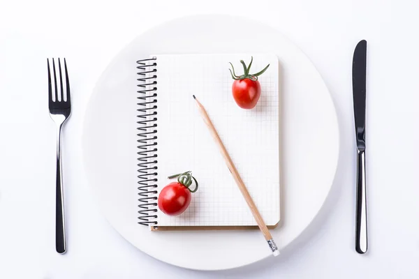 Assiette, fourchette, couteau, tomates, crayon et ruban pour ordinateur portable sur bois — Photo