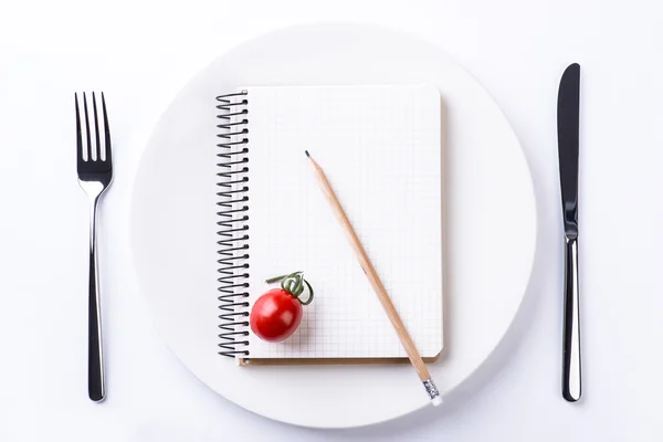 Assiette, fourchette, couteau, tomate, crayon et bloc-notes sur t en bois — Photo