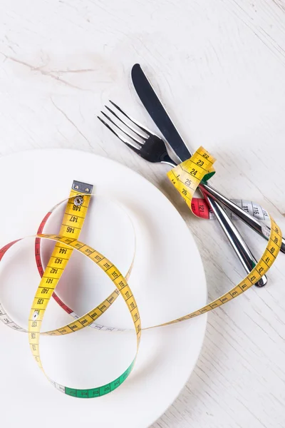 Placa, tenedor, cuchillo y cinta métrica en mesa de madera — Foto de Stock