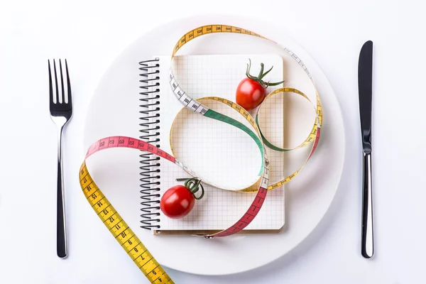 Assiette, fourchette, couteau, ruban à mesurer, tomates et cahier sur bois — Photo