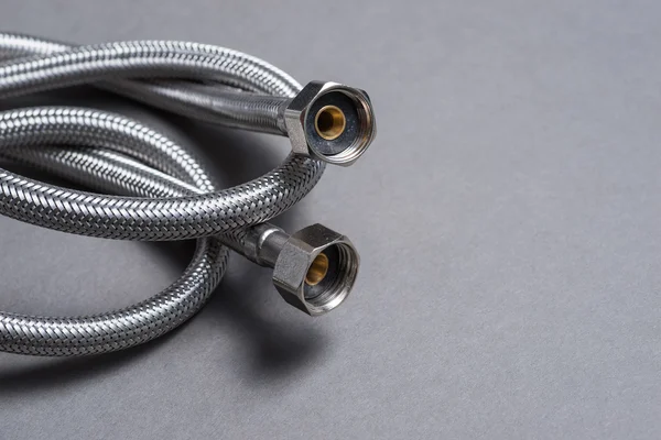 Braided stainless steel water hose over grey background — Stock Photo, Image