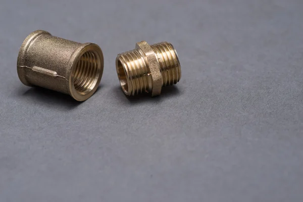 Brass plumbing fittings on grey table — Stock Photo, Image