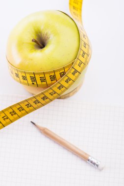 Teyp ve beyaz üstünde defter ölçümleme ile taze ve yeşil organik elma