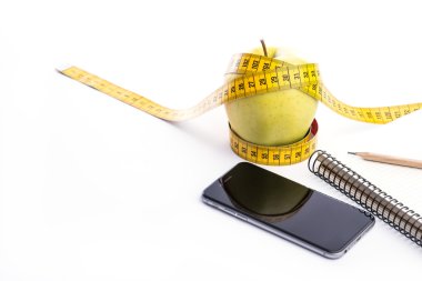 Bant, telefon ve beyaz üstünde defter ölçümleme ile taze ve yeşil organik elma