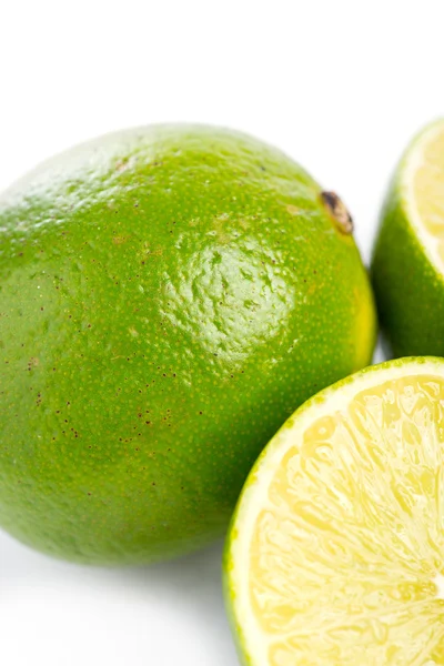 Lime fresche intere e affettate su bianco, DOF — Foto Stock