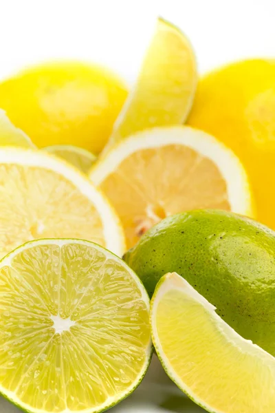 Limes freschi interi e affettati e limoni su bianco, DOF — Foto Stock