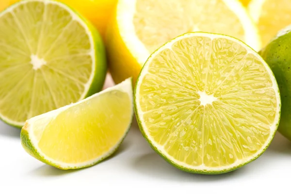 Limes freschi interi e affettati e limoni su bianco, DOF — Foto Stock