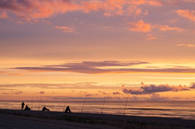 Okyanus, ağır bulutları ile dramatik gün batımında balıkçılar
