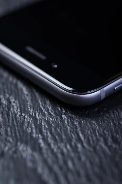 Black smart-phone on a wooden table — Stock Photo, Image