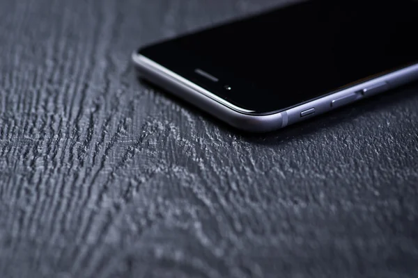 Black smart-phone on a wooden table — Stock Photo, Image