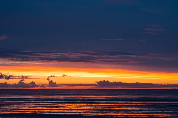 Драматический закат с тяжелыми облаками в океане — стоковое фото
