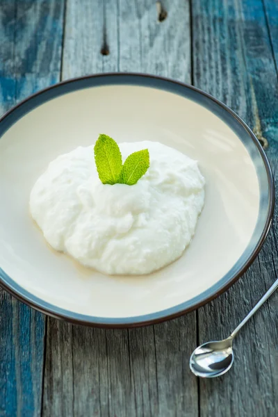 Teller mit frischem Joghurt auf Holztisch — Stockfoto