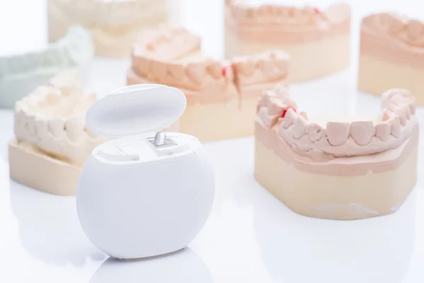 Mallen van de tanden met tandzijde op een helder witte tafel — Stockfoto