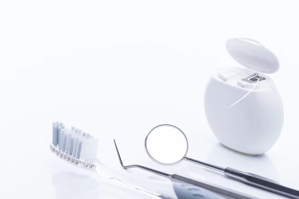 Diş ipi ve fırça ile beyaz bir tablo temel diş araçları — Stok fotoğraf