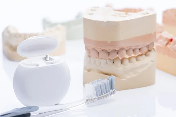 Mallen van de tanden met tandzijde en penseel op een helder witte tafel — Stockfoto