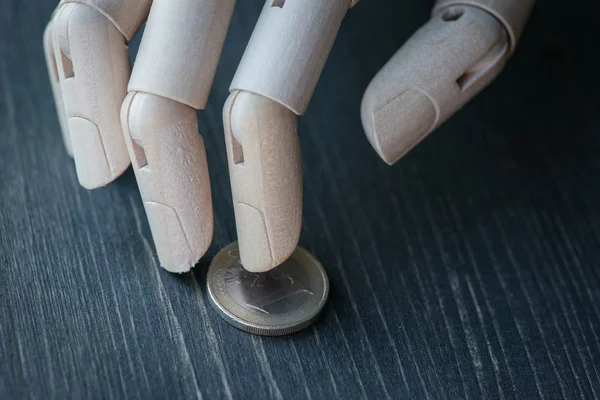 Mano de madera artificial sosteniendo el dinero, sobre una mesa de madera — Foto de Stock