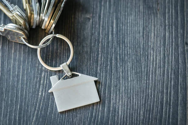 Svazek klíčů s domem tvarovaná klíčenka na dřevěný stůl — Stock fotografie