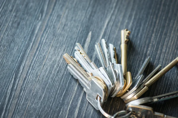 Bunch of keys with house shaped key ring on a wooden table — Stock Photo, Image