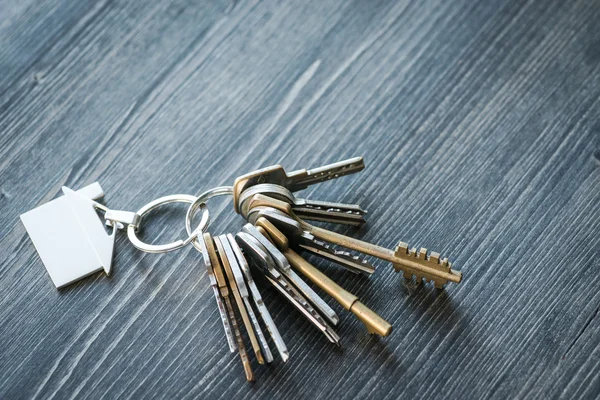 Bunch of keys with house shaped key ring on a wooden table — Stock Photo, Image